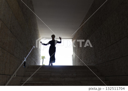 Woman dancing, emerging from dark passage into light Woman dancing, emerging from dark passage into light 132511704