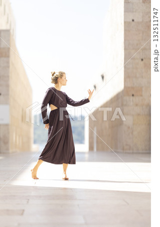Young woman dancing gracefully between modern buildings Young woman dancing gracefully between modern buildings 132511747