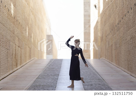 Woman dancing freely in stone passage towards light Woman dancing freely in stone passage towards light 132511750