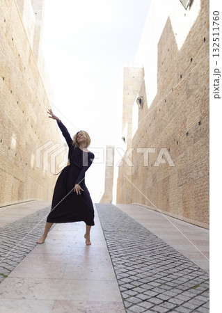 Woman dancing barefoot on stone street path Woman dancing barefoot on stone street path 132511760
