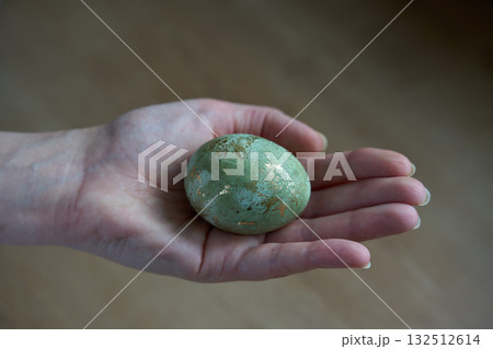 Hand holding decorative egg with golden speckles. Hand holding decorative egg with golden speckles. 132512614