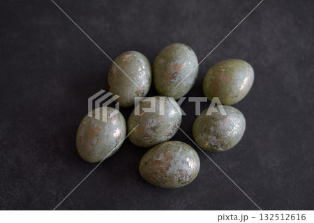 Easter theme. Metallic decorative eggs on dark surface. Easter theme. Metallic decorative eggs on dark surface. 132512616