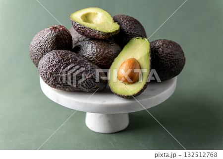 Fresh ripe avocados on marble stand with green background Fresh ripe avocados on marble stand with green background 132512768