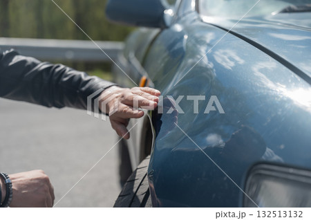 A Caucasian man inspects damage to his car. A Caucasian man inspects damage to his car. 132513132