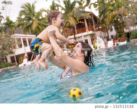 Caucasian woman holds her son while swimming in a pool on vacation. Mom teaches little boy to swim. Caucasian woman holds her son while swimming in a pool on vacation. Mom teaches little boy to swim. 132513138
