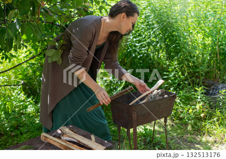 Caucasian woman chopping wood to light a barbecue. Caucasian woman chopping wood to light a barbecue. 132513176
