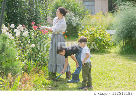 Caucasian woman tending her garden with her sons.  132513188