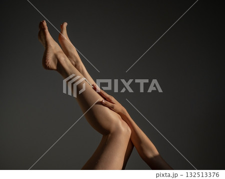 Woman applying moisturizer to her legs. Woman applying moisturizer to her legs. 132513376