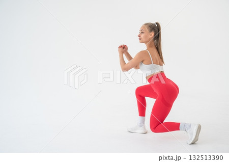 Young woman doing lunges on white cyclorama background. Vertical video. Young woman doing lunges on white cyclorama background. Vertical video. 132513390