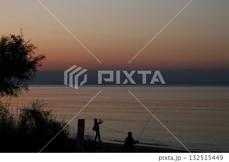 Silhouetted fishermen at sunset on the coast 132515449
