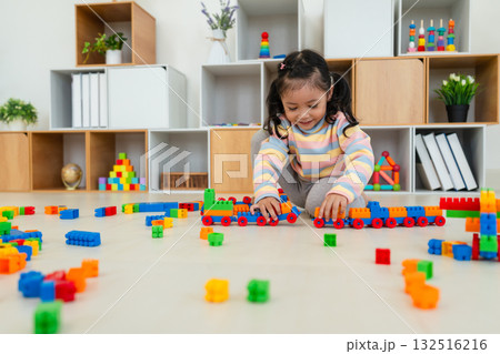 toddler girl playing building blocks or plastic bricks toy at home 132516216
