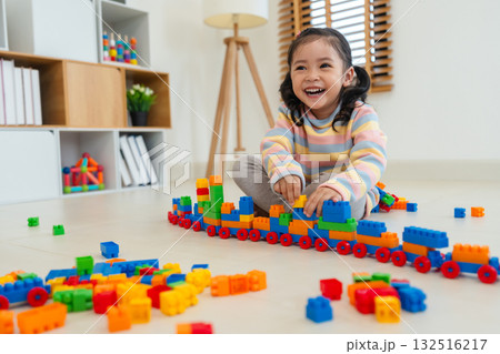 toddler girl playing building blocks or plastic bricks toy at home 132516217