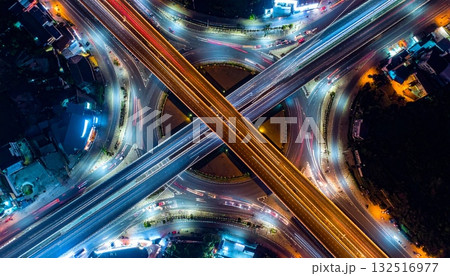 Fast traffic blurs on the city highway at night, forming bright light trails across the dark urban cityscape Fast traffic blurs on the city highway at night, forming bright light trails across the dark urban cityscape 132516977