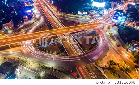 Fast traffic blurs on the city highway at night, forming bright light trails across the dark urban cityscape 132516979