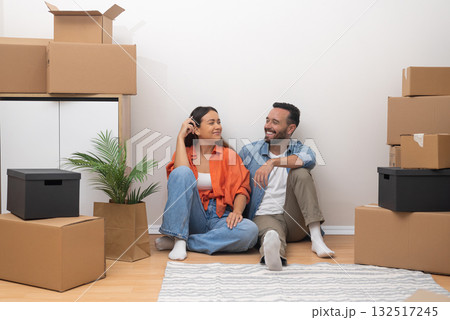 Joyful young couple in their freshly rented apartment, happily looking to each other with moving boxes. Bright, modern living space filled with promise Joyful young couple in their freshly rented apartment, happily looking to each other with moving boxes. Bright, modern living space filled with promise 132517245