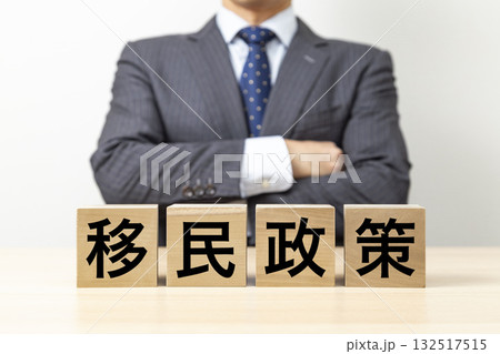 「移民政策」と書かれたブロックと腕組みをするビジネスマン 132517515