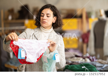 Positive female client choosing new panties in lingerie store 132517952