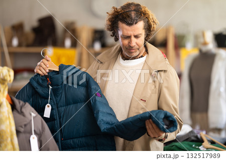 Man choosing a down jacket in a clothing store 132517989