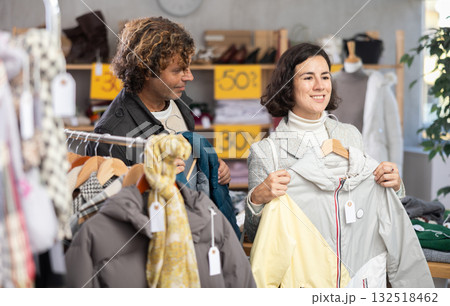 Woman choose down jacket in store, husband give advice and help to choose goods. Woman choose down jacket in store, husband give advice and help to choose goods. 132518462