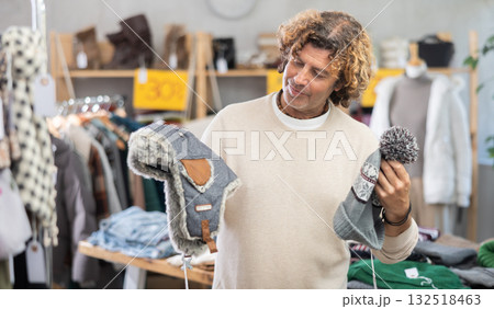 Curly man choosing a hat in the store Curly man choosing a hat in the store 132518463