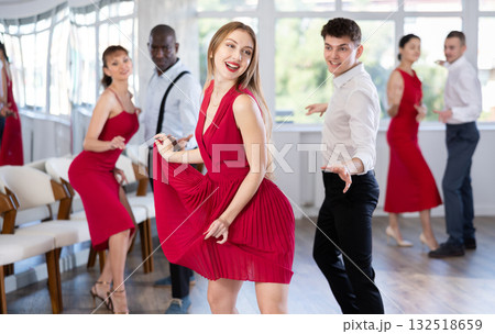 Group of young active people practicing vogue dancing movements while training twist or charleston in dance hall 132518659