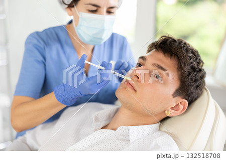 Young man having face care by means of injection in aesthetic clinic Young man having face care by means of injection in aesthetic clinic 132518708
