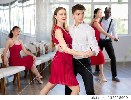 Smiling couple enthusiastically dancing social latin cha-cha-cha dance in dance salon 132518909
