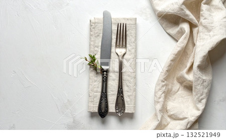 リネンのナプキンの上に置かれたアンティークなフォークとナイフ 132521949