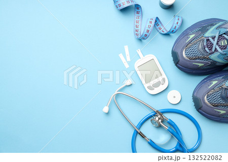 Diabetes monitoring tools and sports shoes on blue surface 132522082
