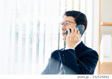 スマホで通話する中高年のビジネスマン スマホで通話する中高年のビジネスマン 132524642