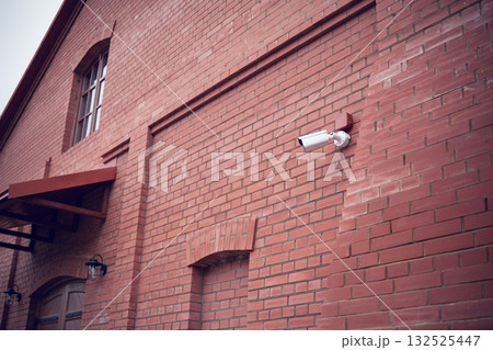 Security camera on the wall of a brick building Security camera on the wall of a brick building 132525447