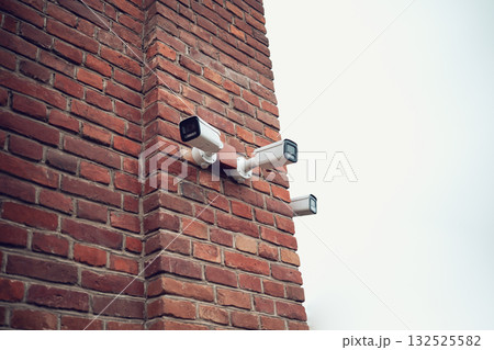 Security camera on the wall of a brick building 132525582