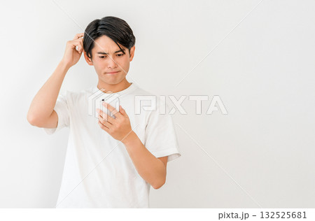 スマホを見ながら考える,検討する,悩む若いアジア人男性 132525681