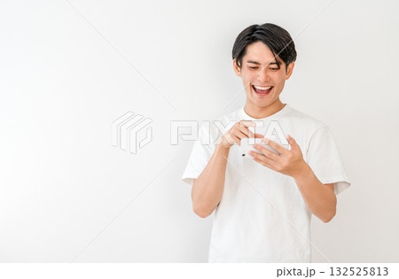 スマホで動画を見ながら笑う若いアジア人男性 スマホで動画を見ながら笑う若いアジア人男性 132525813
