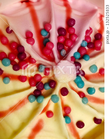 Yellow and pink ice cream swirls with colorful round sprinkles. Yellow and pink ice cream swirls with colorful round sprinkles. 132525833