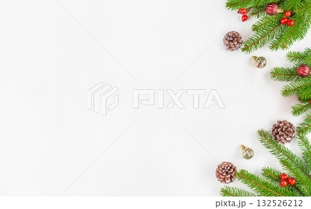 Minimalistic Christmas background with fir branches, pine cones, red berries, and ornaments on white surface, festive flat lay composition with copy space for holiday greeting or winter design 132526212