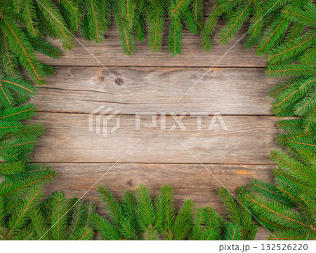 Christmas background with green fir branches forming a natural frame on rustic wooden table, top view, copy space for text or holiday design Christmas background with green fir branches forming a natural frame on rustic wooden table, top view, copy space for text or holiday design 132526220