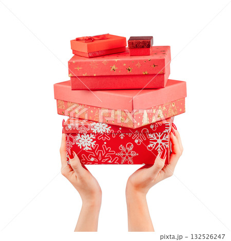 Female hands holding a stack of red gift boxes with festive wrapping and gold accents, isolated on white background. Christmas or holiday presents concept symbolizing generosity and celebration Female hands holding a stack of red gift boxes with festive wrapping and gold accents, isolated on white background. Christmas or holiday presents concept symbolizing generosity and celebration 132526247