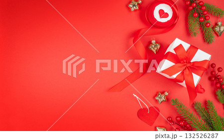 Christmas flat lay with red gift box, ribbon, fir branches, berries, and heart decorations on red background, festive composition with copy space for text, top view minimal holiday scene Christmas flat lay with red gift box, ribbon, fir branches, berries, and heart decorations on red background, festive composition with copy space for text, top view minimal holiday scene 132526287