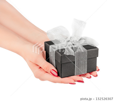 Female hands holding small black gift box with silver ribbon bow isolated on white background elegant minimal concept for luxury present, Christmas, birthday romantic celebration design Female hands holding small black gift box with silver ribbon bow isolated on white background elegant minimal concept for luxury present, Christmas, birthday romantic celebration design 132526307