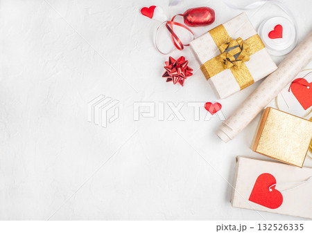 Romantic festive flat lay with gift boxes wrapped in gold and white paper, red ribbons, heart decorations on white background copy space concept Valentines Day, Christmas anniversary celebration 132526335