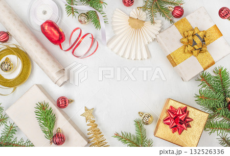 Festive Christmas flat lay with gift boxes, golden and red ribbons, baubles, fir branches, and paper angel decoration on white background with copy space holiday celebration concept Festive Christmas flat lay with gift boxes, golden and red ribbons, baubles, fir branches, and paper angel decoration on white background with copy space holiday celebration concept 132526336