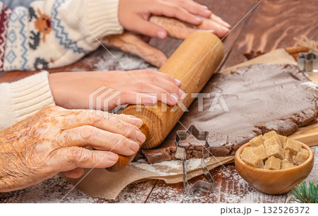 Generational hands working together to roll gingerbread dough, symbolizing family connection, tradition, and shared holiday baking moments 132526372