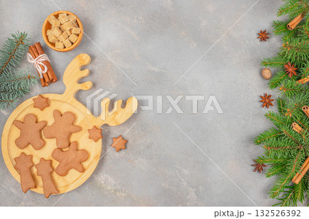 homemade Christmas gingerbread cookies on a wooden reindeer board with sugar cubes, cinnamon sticks, star anise and fir branches on a gray background copy space homemade Christmas gingerbread cookies on a wooden reindeer board with sugar cubes, cinnamon sticks, star anise and fir branches on a gray background copy space 132526392