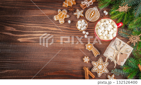 Festive Christmas composition with hot cocoa and marshmallows, gingerbread cookies, gift box, and fir branches on a rustic wooden background. copy space. top view 132526400