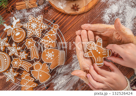 Generational connection and holiday tradition concept with elderly and young hands holding a gingerbread cookie together, symbolizing love, family bonding, heritage, and Christmas spirit 132526424