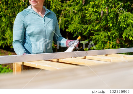 Woman painting a wooden pallet outdoors for a DIY project in her sunny tranquil backyard Woman painting a wooden pallet outdoors for a DIY project in her sunny tranquil backyard 132526963