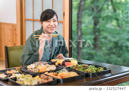テーブルいっぱいの食事を嬉しそうに食べる浴衣姿の若い女性 テーブルいっぱいの食事を嬉しそうに食べる浴衣姿の若い女性 132527447