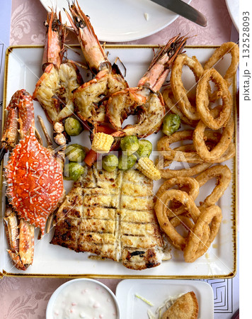 Grilled seafood platter with prawns, crab, fish fillet, fried calamari rings, vegetables. Seafood menu. Top view. Grilled seafood platter with prawns, crab, fish fillet, fried calamari rings, vegetables. Seafood menu. Top view. 132528093
