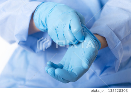 Healthcare professional putting on blue medical gloves on white background with copy space 132528308